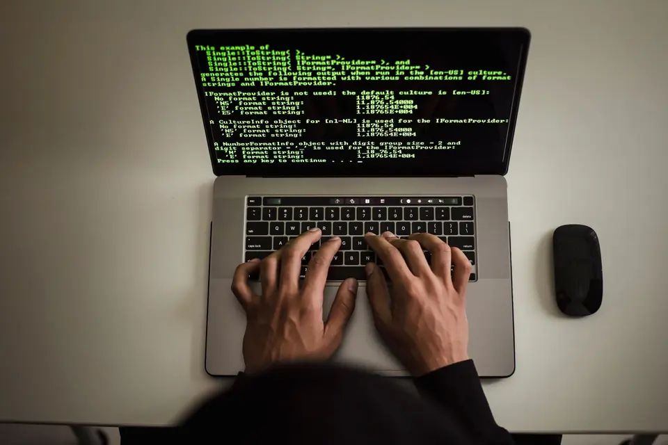 Mains sur le clavier d'un ordinateur portable affichant du code